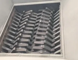 Industrial shredding system integrated with a conveyor belt for automatic material feeding.